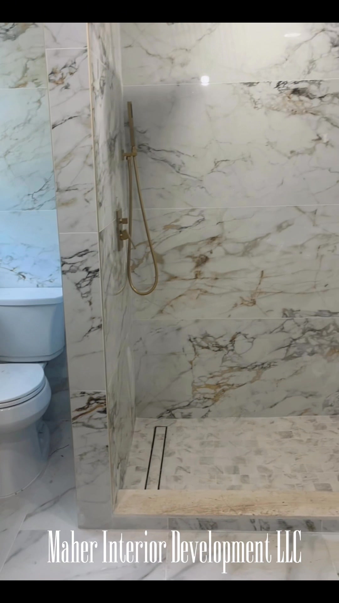 Finished bathroom with book-matched marble tile walls, curbless shower and linear drain