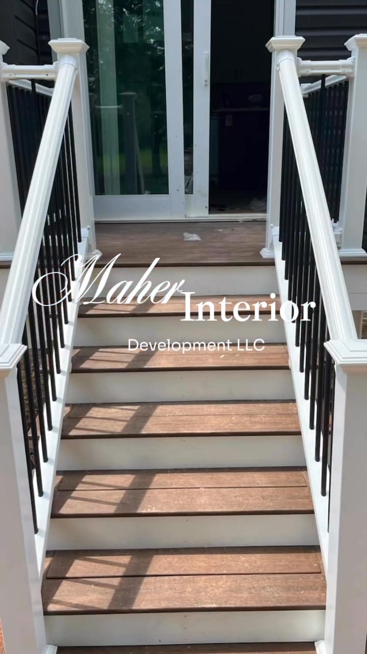 Composite deck stairs with white posts and black balusters leading to a rear entry