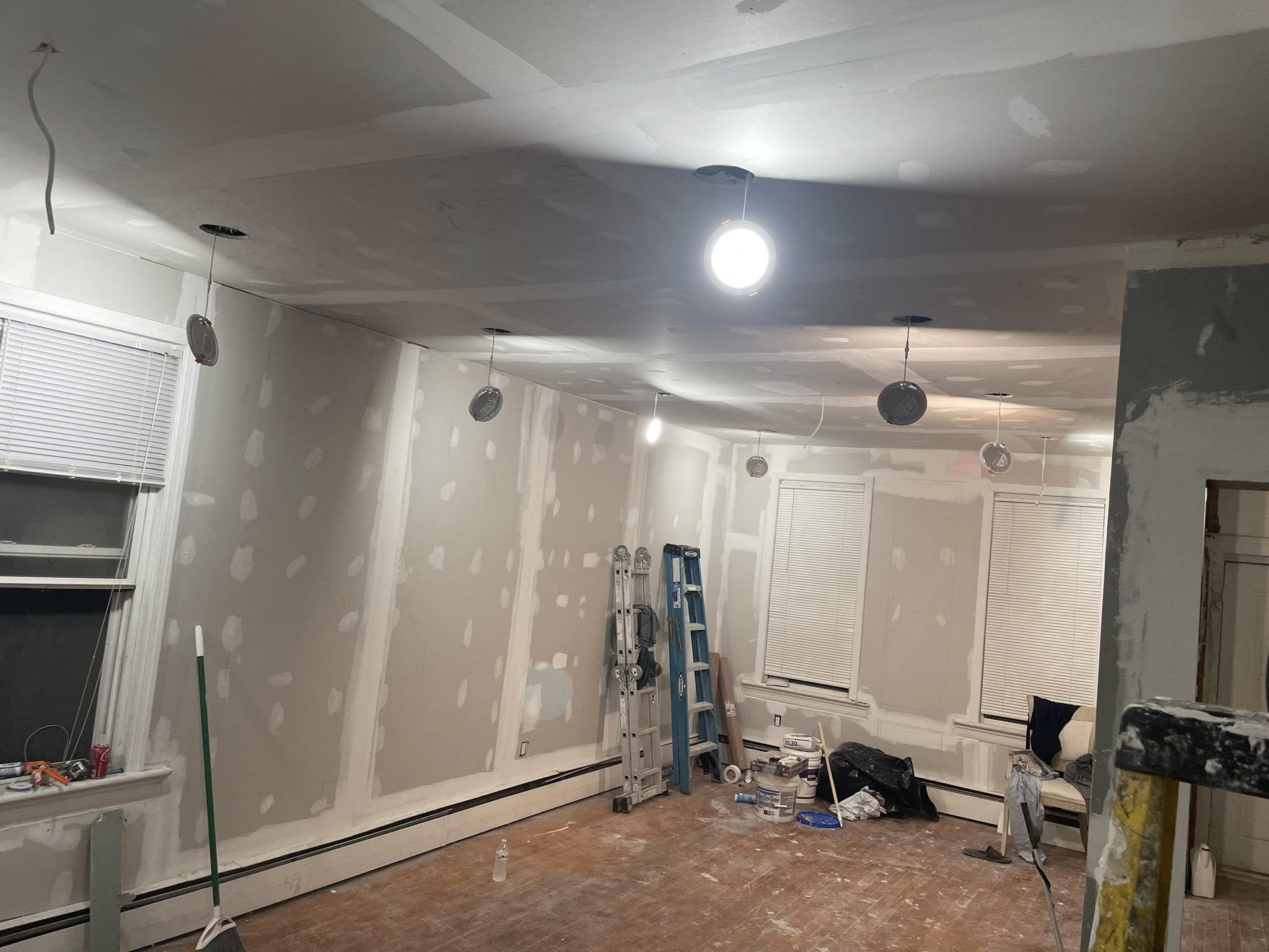 Room with newly hung and taped drywall and recessed lighting cans roughed in