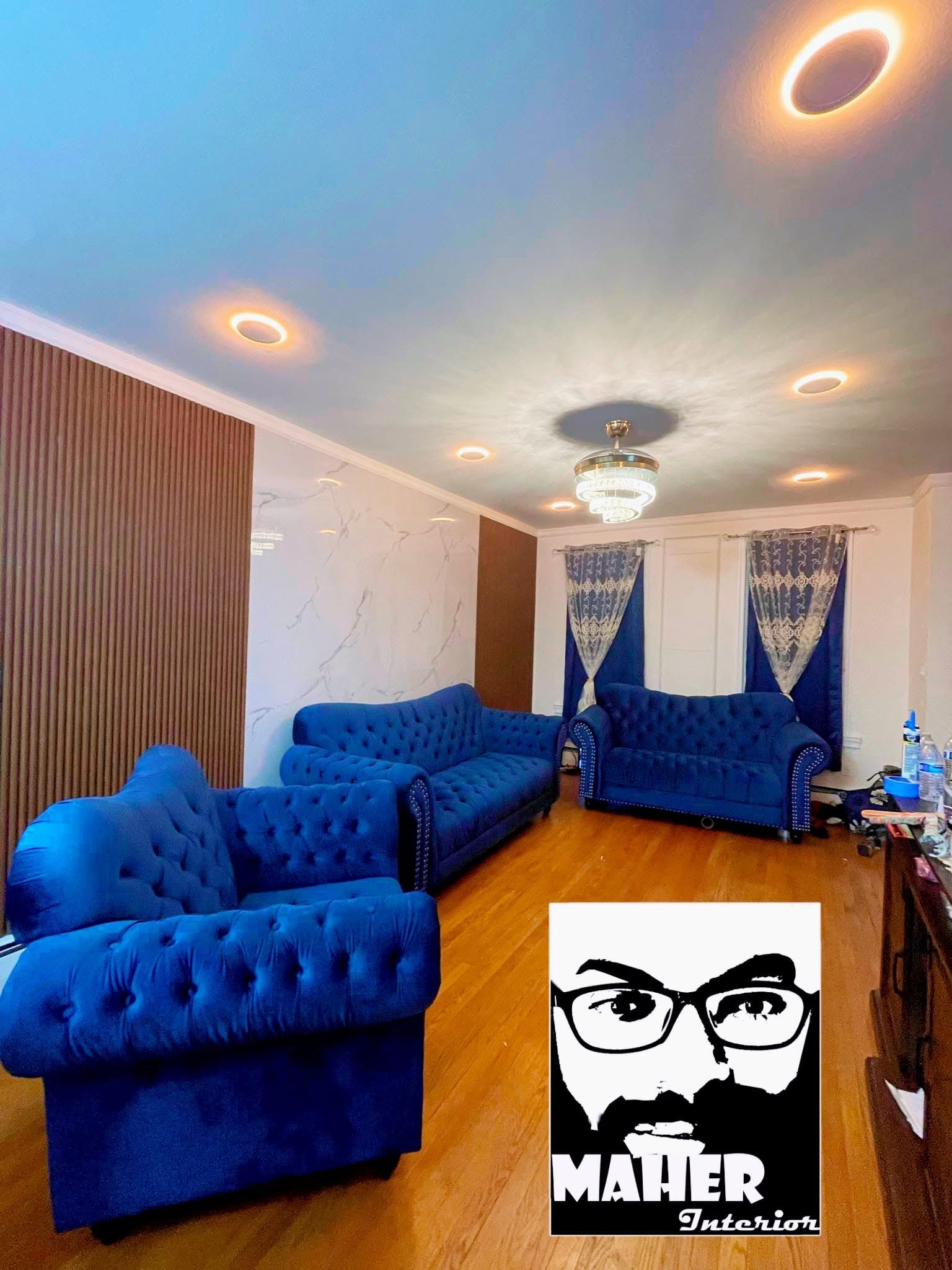 Finished living room with wood slat accent walls, marble panel, crown molding and recessed lighting